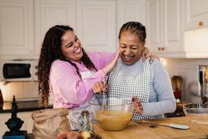 Happy African mother and daughter having fun preparing a homemade dessert photo