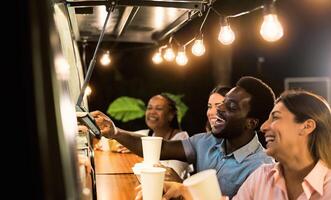 Happy multiracial people buying meal from food truck kitchen - Modern business and take away concept photo