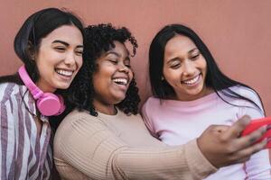 Happy Hispanic friends having fun taking selfie with mobile smartphone outdoor - Technology and social media concept photo