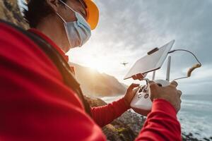 Male engineer monitoring the drone inspection while wearing face mask to avoid corona virus spreading - Technology and industrial concept photo