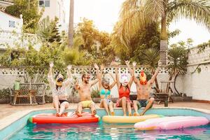 Group happy friends making pool party - Young people having fun celebrating carnival event in exclusive swimmingpool summer tropical vacation - Friendship and youth holidays lifestyle concept photo