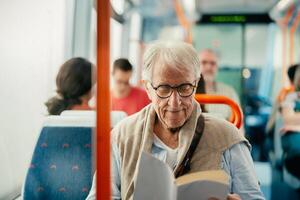 mayor hombre leyendo libro mientras de viaje con autobús foto