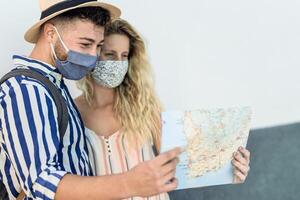 Travel young couple holding city map during a journey while wearing face mask for preventing corona virus photo