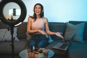 Female influencer vlogging online  with smartphone cam and laptop from home - Youth people with social media and smart working concept photo
