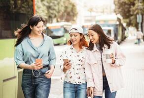 contento asiático muchachas utilizando móvil teléfono al aire libre - joven milenario personas teniendo divertido con nuevo teléfono inteligente aplicación tecnología - concepto de amistad, social, tecnología y adolescente estilo de vida foto