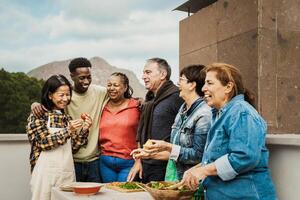 Multi generational friends having fun cooking together at house rooftop - Summer gatherings and food concept photo