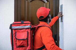 African rider man delivering meal to customers home while wearing face mask during corona virus outbreak - Delivery food concept photo