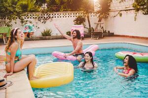contento amigos teniendo divertido en nadando piscina durante verano vacaciones - joven personas relajante y flotante en aire lilo durante en el piscina recurso - amistad, Días festivos y juventud estilo de vida concepto foto