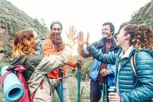 grupo de amigos apilado manos mientras haciendo trekking excursión en montaña - joven turistas caminando y explorador el salvaje naturaleza - excursionista, equipo, caminata y viaje personas concepto foto