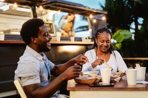 contento africano madre y hijo teniendo divertido comiendo en un calle comida camión mercado al aire libre foto