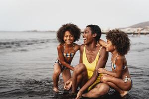 Happy African family having fun on the beach during vacations - Lovely family lifestyle concept photo