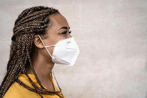 African woman with braids wearing face medical mask - Young girl using facemask for preventing and stop corona virus spread - Healthcare medical and youth millennial people concept photo