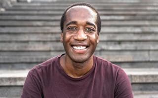 Happy African man smiling into the camera while sitting on urban stairs photo