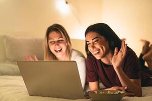 Young women having fun doing video call using laptop in bed during corona virus outbreak photo