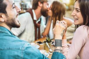 Happy friends drinking cappuccino in cafeteria bar - Young romantic couple having fun sharing time together -  Love relationship and social gathering people lifestyle concept photo