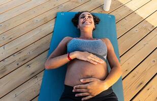 Top view of happy pregnant woman caressing her belly outdoor - Health lifestyle and maternity concept photo