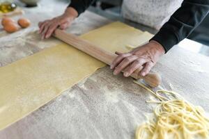 Close up female hands roll the dough preparing fresh homemade pasta photo