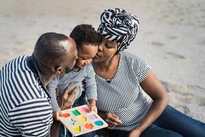 Happy African family having fun on the beach during summer holidays - Parents love concept photo