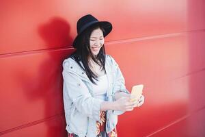 Asian girl using mobile phone outdoor - Happy millennial Chinese woman having fun with new trends smartphone apps - Technology addiction and youth generation culture people lifestyle concept photo