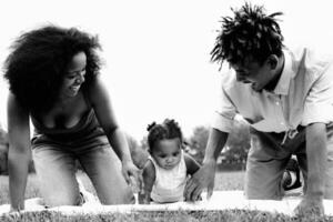 contento africano familia teniendo divertido juntos en público parque - negro padre y madre disfrutando hora con su hija foto