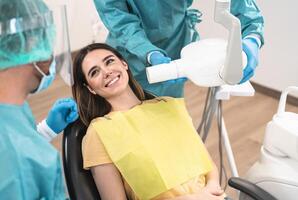 hombre dentista operando joven sonriente mujer en dental clínica - oral atención a la salud asistencia concepto foto