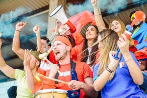 Football supporter fans watching world soccer match at stadium - Young group of excited friends having fun exulting at international sport game - Concept of youth people celebrating club winner photo