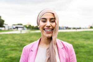 Happy Muslim woman having fun while posing in front of camera in a park photo