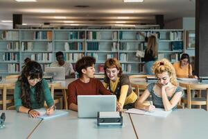 Young university students using laptop and studying with books in library - School education concept photo