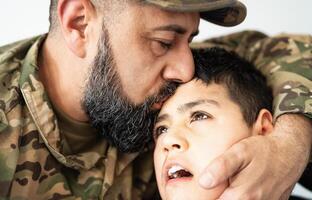 Military soldier kissing his son with disability at home photo