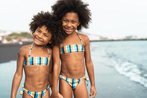 Happy Afro children having fun on the beach during summer time - Childhood and vacation concept photo