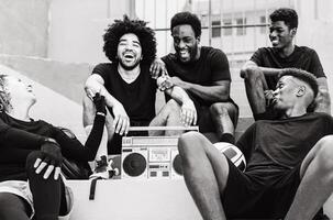 Group of multiracial people having fun listening music with vintage boombox stereo - Urban street people lifestyle - Black and white editing photo