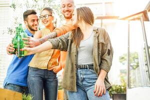 Happy friends cheering with beers in bar restaurant outdoor - Young people having fun drinking and toasting alcohol - Concept of youth friendship lifestyle photo