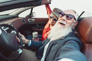 contento mayor Pareja tomando selfie en nuevo convertible coche - maduro personas teniendo divertido juntos durante la carretera viaje vacaciones - mayor estilo de vida y viaje transporte concepto foto