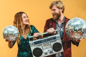 Happy young couple celebrating holidays listening music with vintage boombox photo