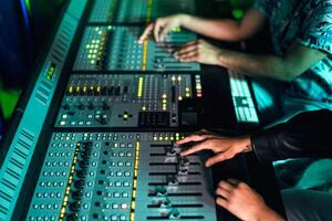 Close up audio engineer hands working with panel mixer control in music recording studio photo