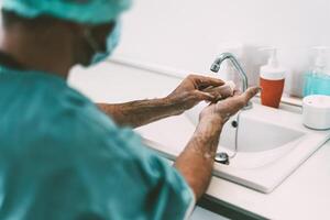 Surgeon washing hands before operating patient in hospital - Medical worker getting ready for fighting against corona virus pandemic - Health care and hygiene concept photo