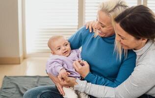 Happy lesbian couple having tender moments with their small baby at home - LGBT Family concept photo