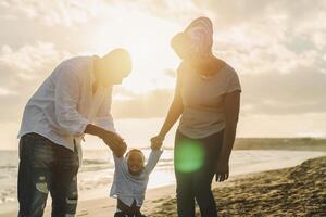 Happy African family having fun on the beach during summer holidays - Parents love concept photo