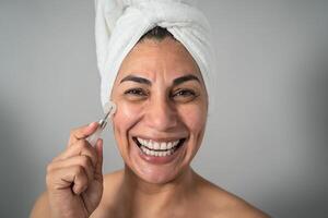 Happy Latin mature woman having skin care spa day - People wellness lifestyle concept photo
