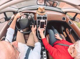 contento mayor Pareja teniendo divertido en nuevo convertible coche - maduro personas disfrutando hora juntos durante la carretera viaje vacaciones - mayor estilo de vida y viaje transporte concepto foto