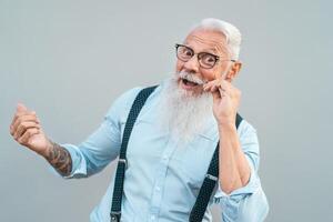 Happy trendy senior man having fun posing in front camera - Fashion beard mature male enjoying retired time - Elderly people lifestyle and hipster culture concept photo