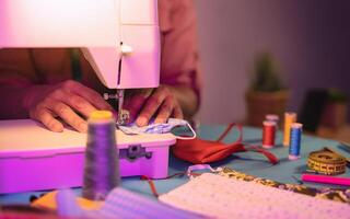 Close up female worker hands working with sewing machine making face medical mask for preventing and stop corona virus spreading - Homemade manufacturing concept photo