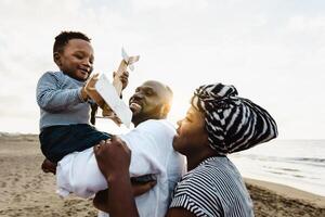 contento africano familia teniendo divertido en el playa durante verano vacaciones - padres amor y unidad concepto foto