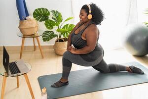 joven africano mujer haciendo pilates virtual aptitud clase con ordenador portátil a hogar - deporte bienestar personas estilo de vida concepto foto