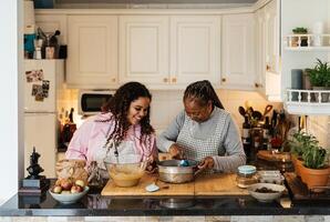 contento africano madre y hija teniendo divertido preparando un hecho en casa postre foto