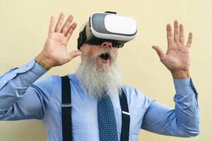 Senior fashion male playing with virtual reality glasses outdoor - Happy aged man having fun with innovated vr googles technology - Tech gaming entertainment concept photo