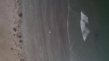 Car driving on black beach view from drone from above video