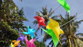 Colorful pinwheels spinning in a tropical setting under a clear blue sky, embodying concepts of childhood, playfulness, and environmental awareness video