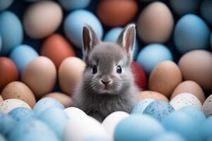 ai generado bebé gris conejito se sienta Entre múltiple de colores huevos foto
