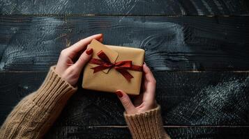 ai generado hembra manos son visto participación un regalo tarjeta y un regalo caja en un negro de madera mesa foto